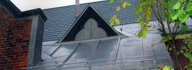 Toiture en ardoise noire avec solins en zinc sur édifice en brique d’architecture gothique